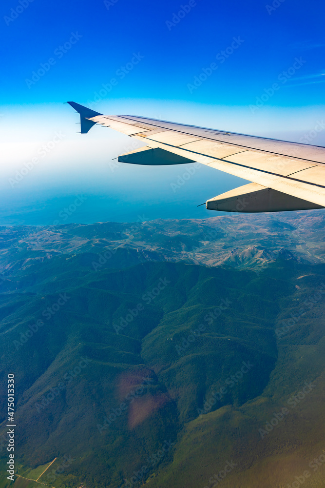 View from the airplane window at a beautiful blue clear sky and the airplane wing View from the airplane window at a beautiful blue clear sky and the airplane wing