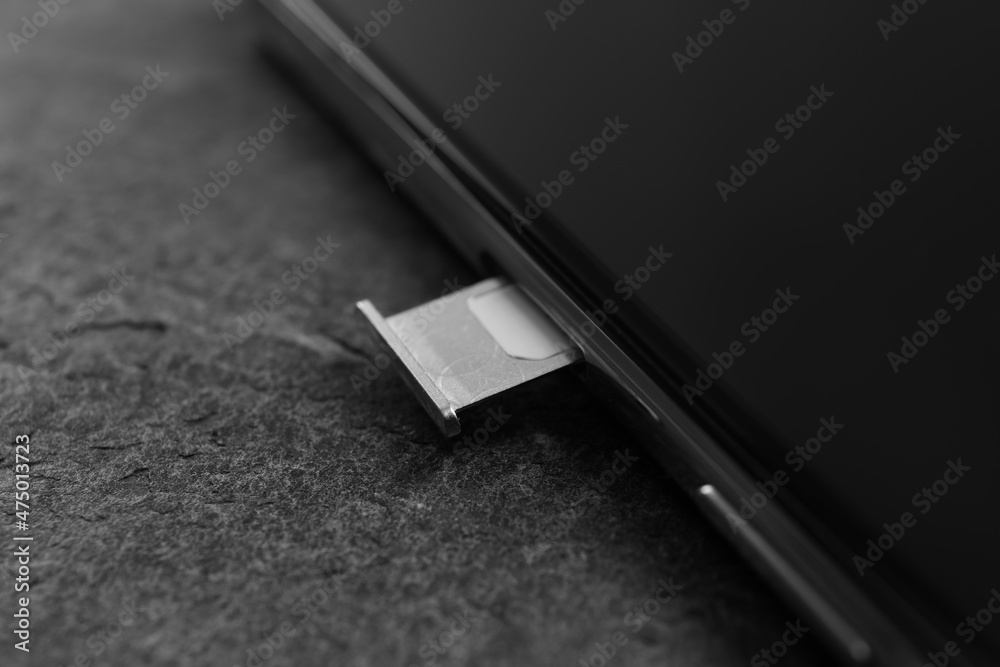 Mobile phone with Sim card in tray on grey table, closeup Mobile phone with Sim card in tray on grey table, closeup