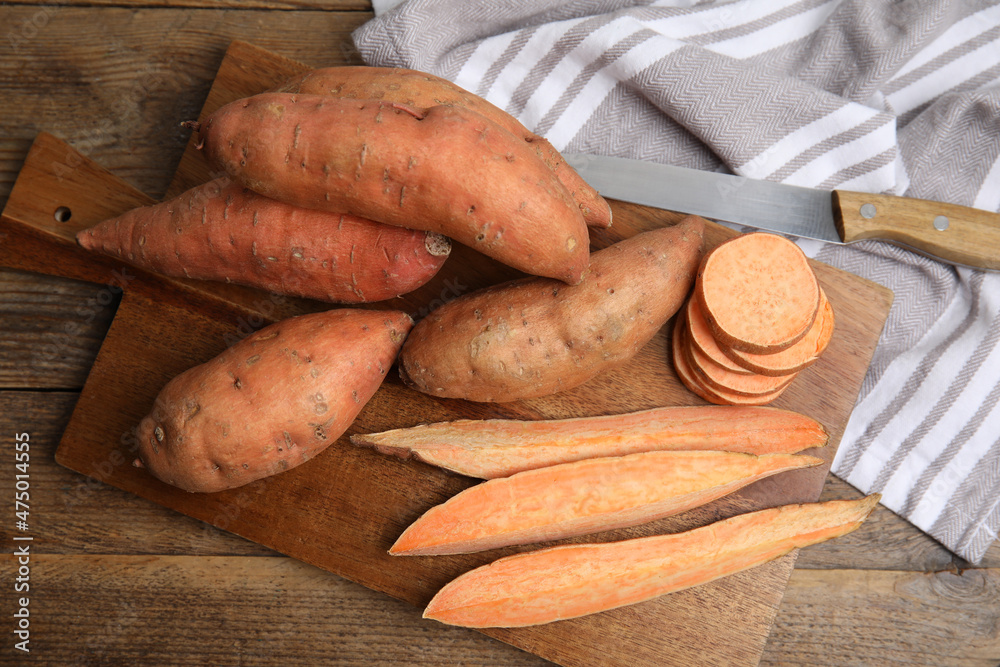 Sweet potatoes and knife on wooden table, flat lay Sweet potatoes and knife on wooden table, flat lay