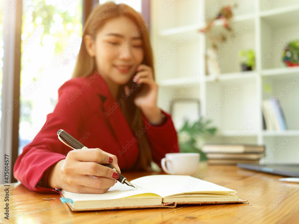 Female assistant taking a notes while talking on the phone Female assistant taking a notes while talking on the phone