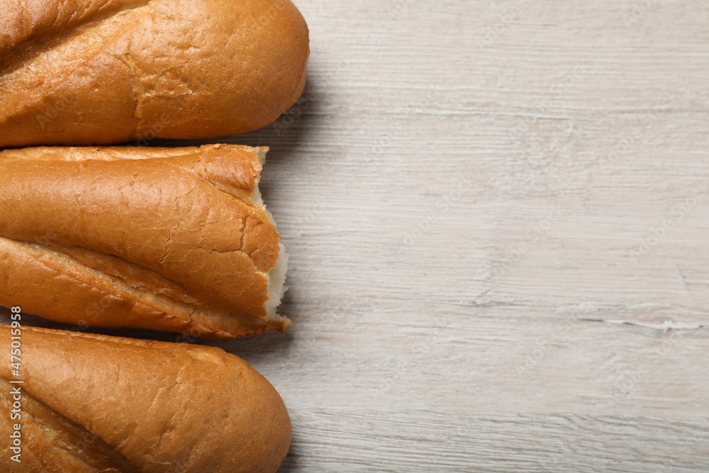 Whole and broken tasty baguettes on white wooden table, flat lay. Space for text Whole and broken tasty baguettes on white wooden table, flat lay. Space for text