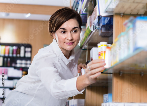 Young glad positive female customer searching for reliable drug in pharmacy