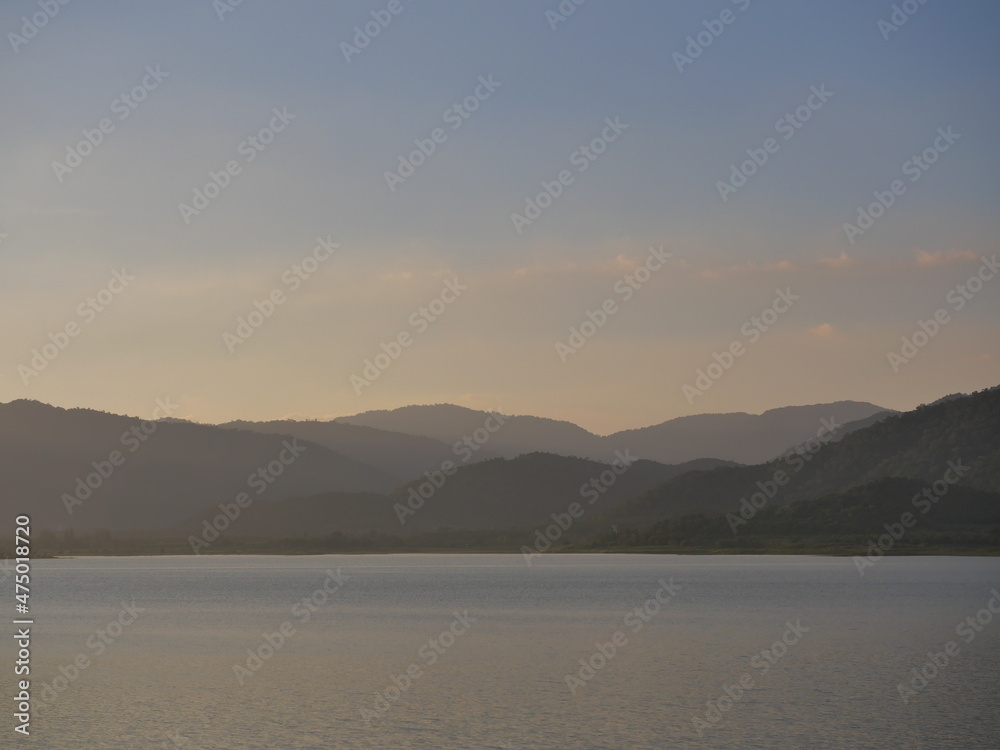 Silhouette of the mountain is reflected on the lake surface at sunset, The surface of the water sparkles with dazzling light