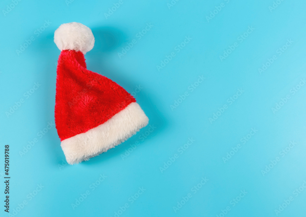 flat lay of bright red Santa Claus hat on blue backgroud. Christmas background.