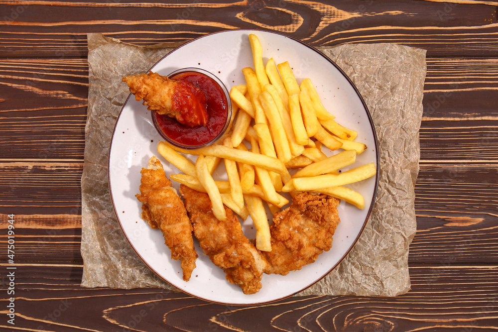 Plate with tasty french fries, deep fried chicken wings and tomato sauce on wooden table Plate with tasty french fries, deep fried chicken wings and tomato sauce on wooden table