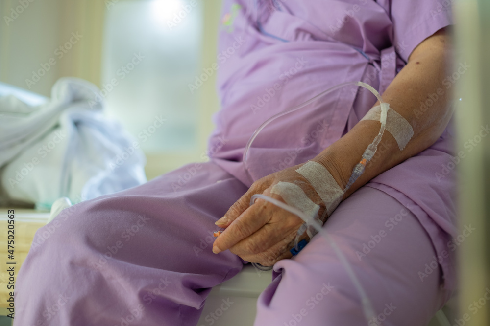 Fototapeta premium giving saline to the hand of an old woman, medical treatment