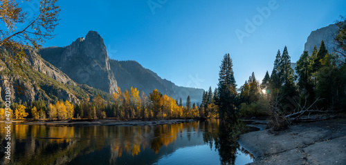 Panoramic View of Fall Season Color Trees Reflected on Water With Mountains in the Background