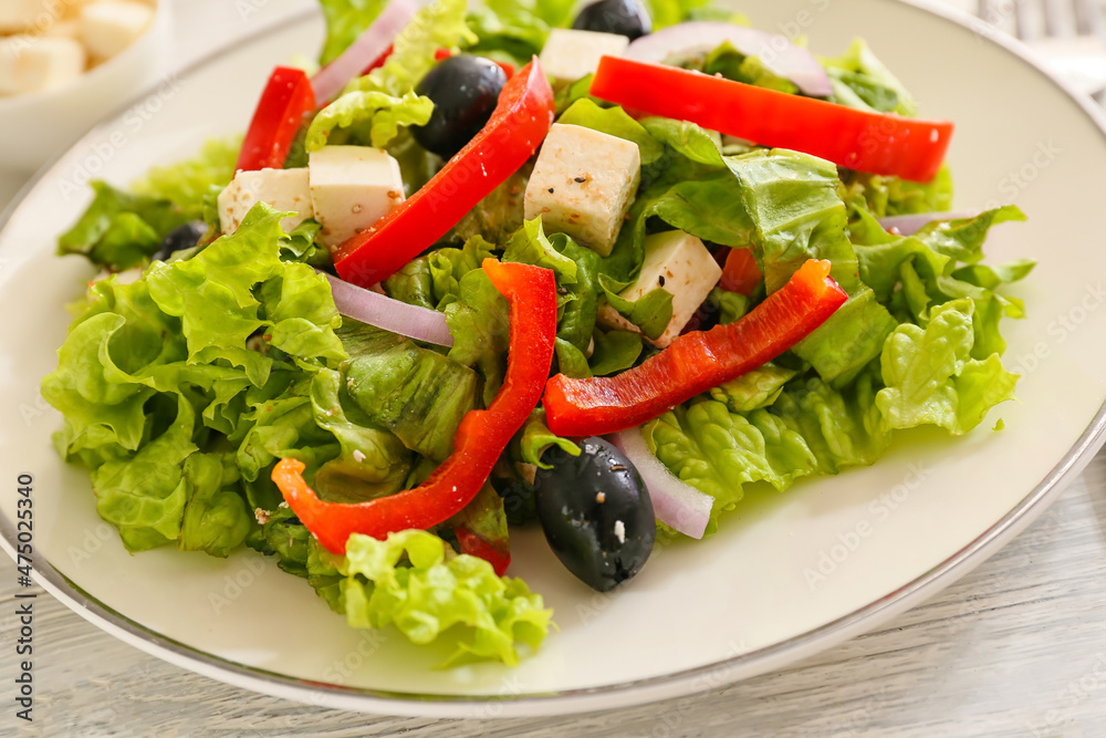 Plate with fresh Greek salad on light wooden background, closeup Plate with fresh Greek salad on light wooden background, closeup