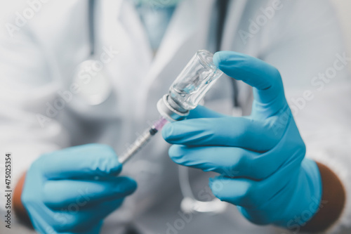 A doctor or scientist in the COVID-19 medical vaccine research and development laboratory holds a syringe with a liquid vaccine to study and analyze antibody samples for the patient. 