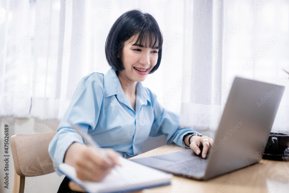 Smiling with dental braces of asian freelance people business female written Notes to on notebook working with laptop computer with coffee cup and smartphone in coffee shop Smiling with dental braces of asian freelance people business female written Notes to on notebook working with laptop computer with coffee cup and smartphone in coffee shop