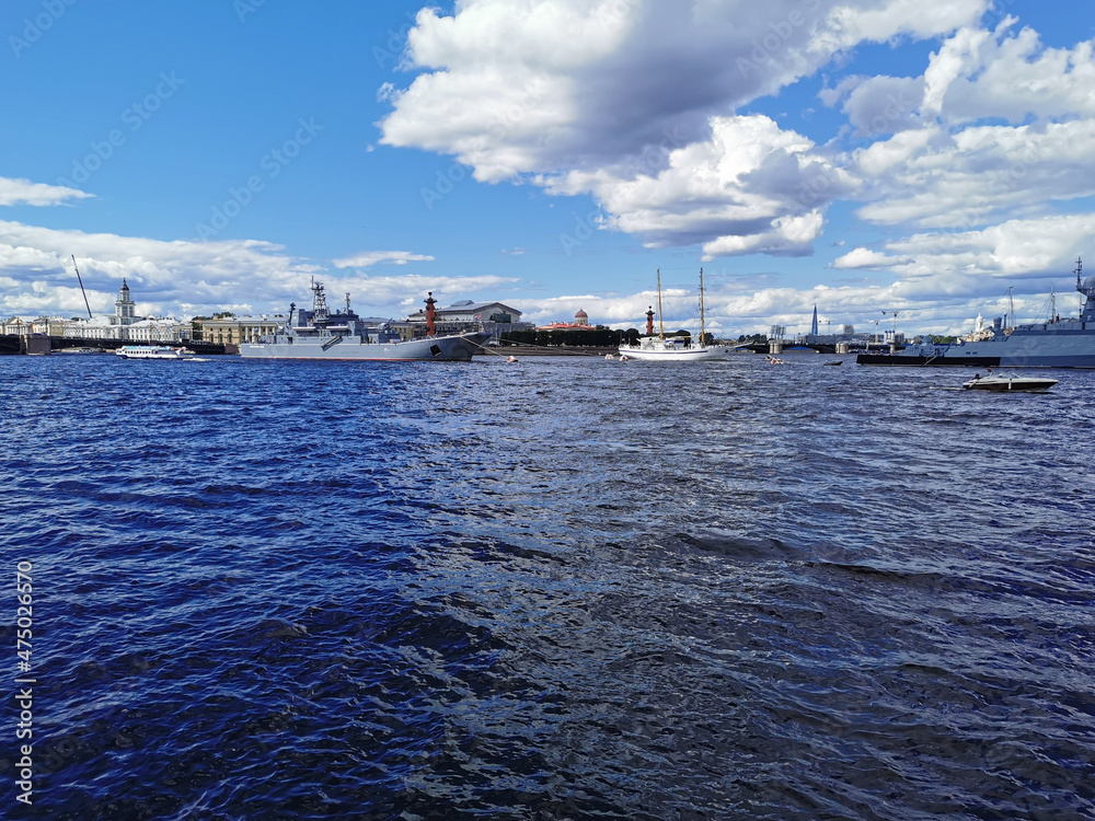 Warships, frigates and sailboats built in the Neva water area for the Day of the Navy in St. Petersburg, there are many pleasure boats around.