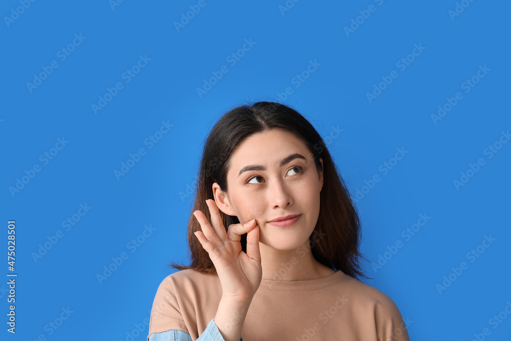 Young Asian woman zipping her mouth on color background Young Asian woman zipping her mouth on color background