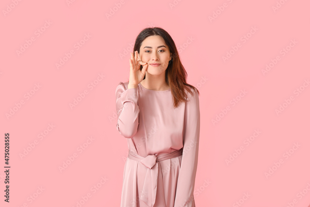 Young Asian woman zipping her mouth on color background Young Asian woman zipping her mouth on color background