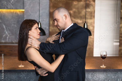 Man strangling  woman. Bald man strangles a dark-haired girl in a restaurant with his hands photo