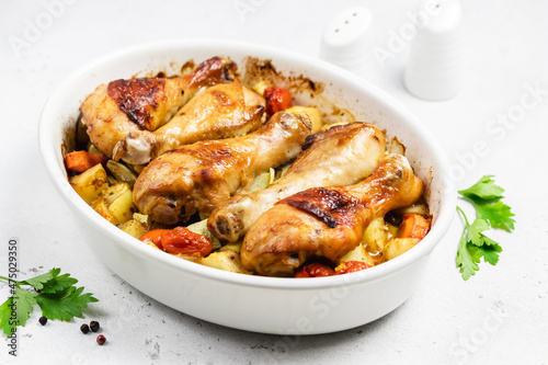 Sweet chili roasted chicken legs with root vegetables in baking dish.Copy space.