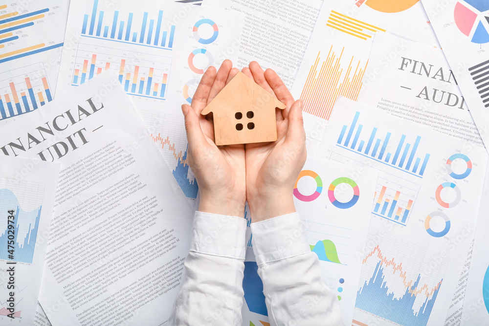 Real estate agent with wooden house on paper sheets Real estate agent with wooden house on paper sheets