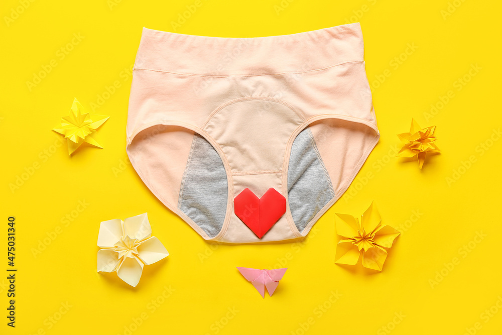 Period panties with origami heart and flowers on color background