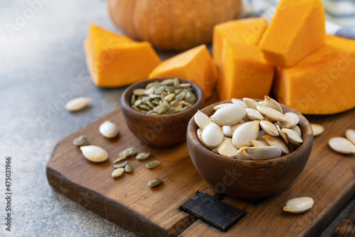 Raw superfoods pumpkin seeds after harvest. Pumpkin seeds in wooden bowl over gray stone background. Copy space.