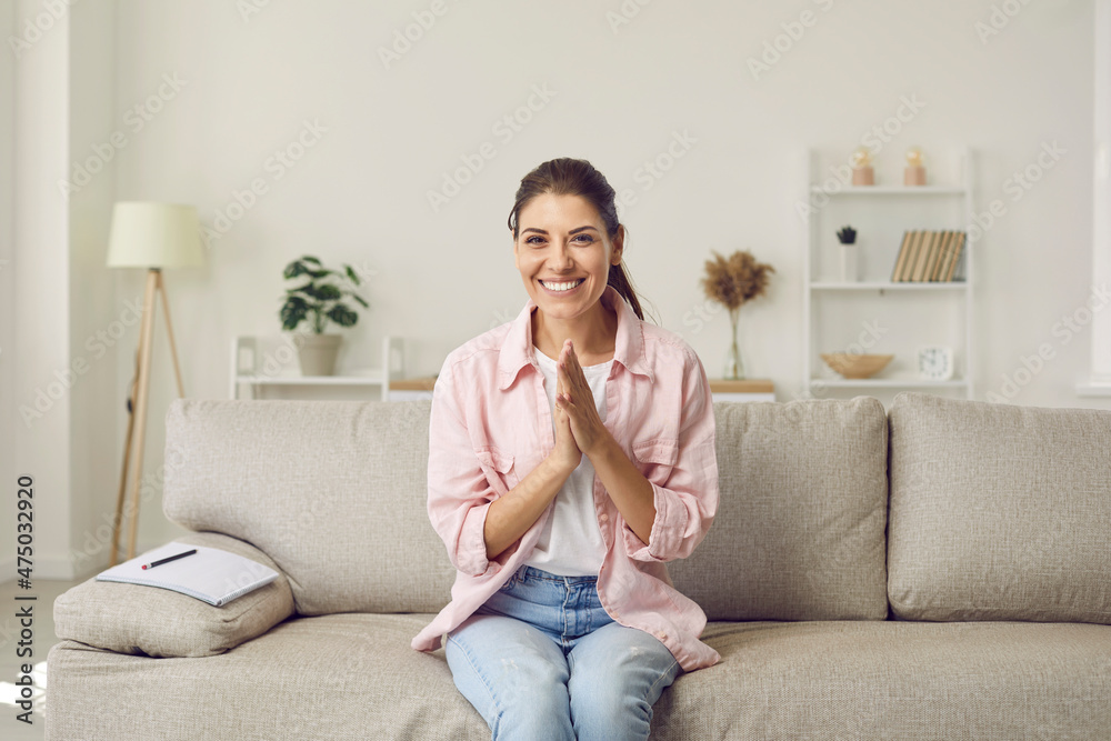 Online webcam view of happy adult woman sitting on sofa with notebook at  home, smiling at