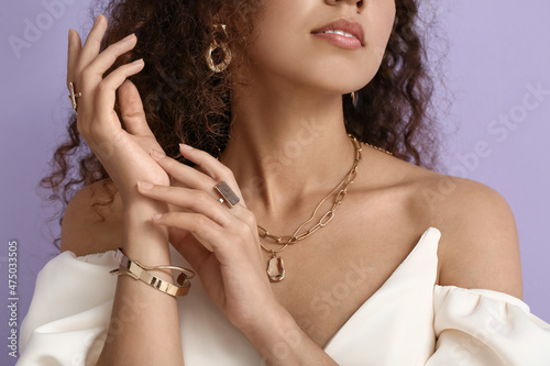 Foto Fashionable African-American woman with stylish jewellery on color background