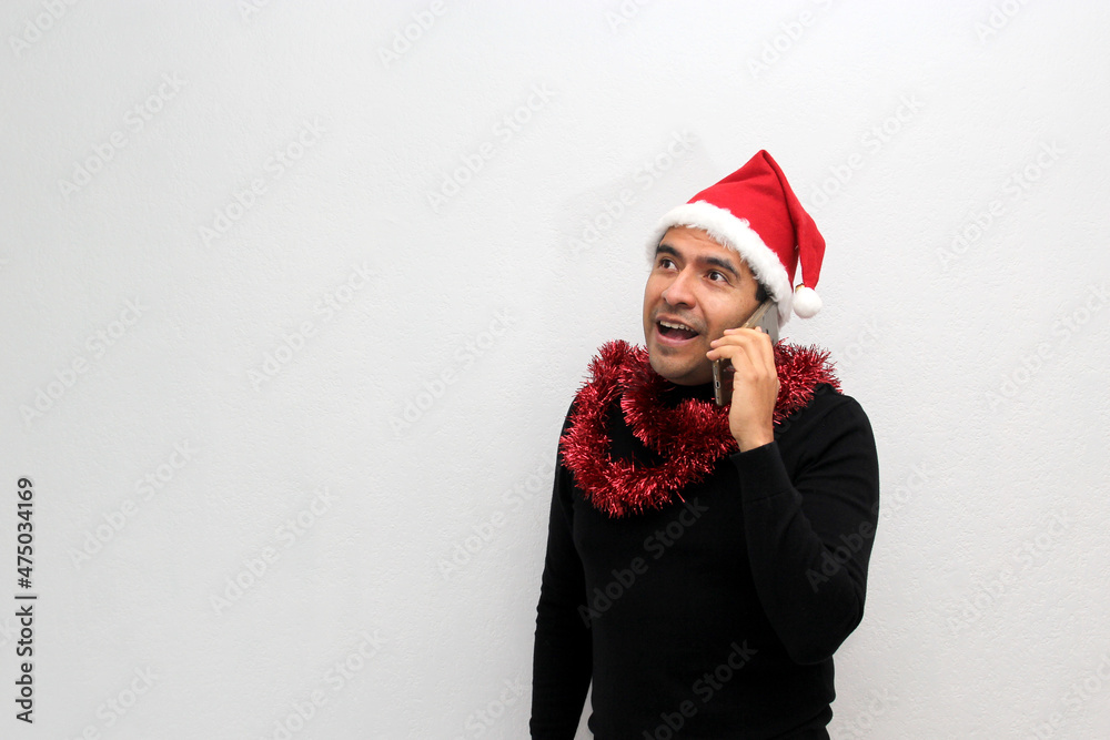 Latino adult man with Christmas hat and red garland as scarf uses his cell phone to call his family with happy video call and excited to celebrate Christmas
Latino adult man with Christmas hat and red garland as scarf uses his cell phone to call his family with happy video call and excited to celebrate Christmas
