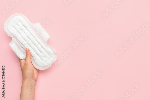 Female hand with menstrual pad on pink background photo