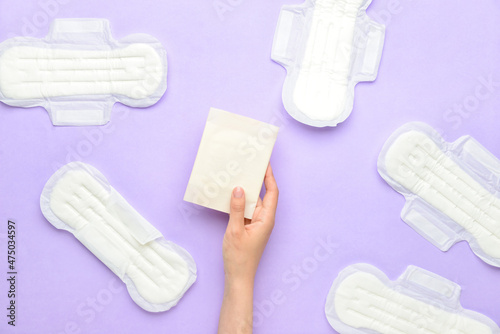 Female hand with menstrual pads on purple background