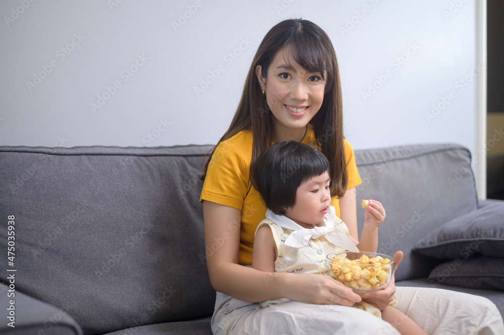 Happy mom and daughter watching movie and relaxing at home Happy mom and daughter watching movie and relaxing at home