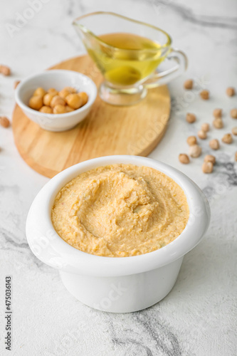 Bowl with delicious hummus on light background  closeup