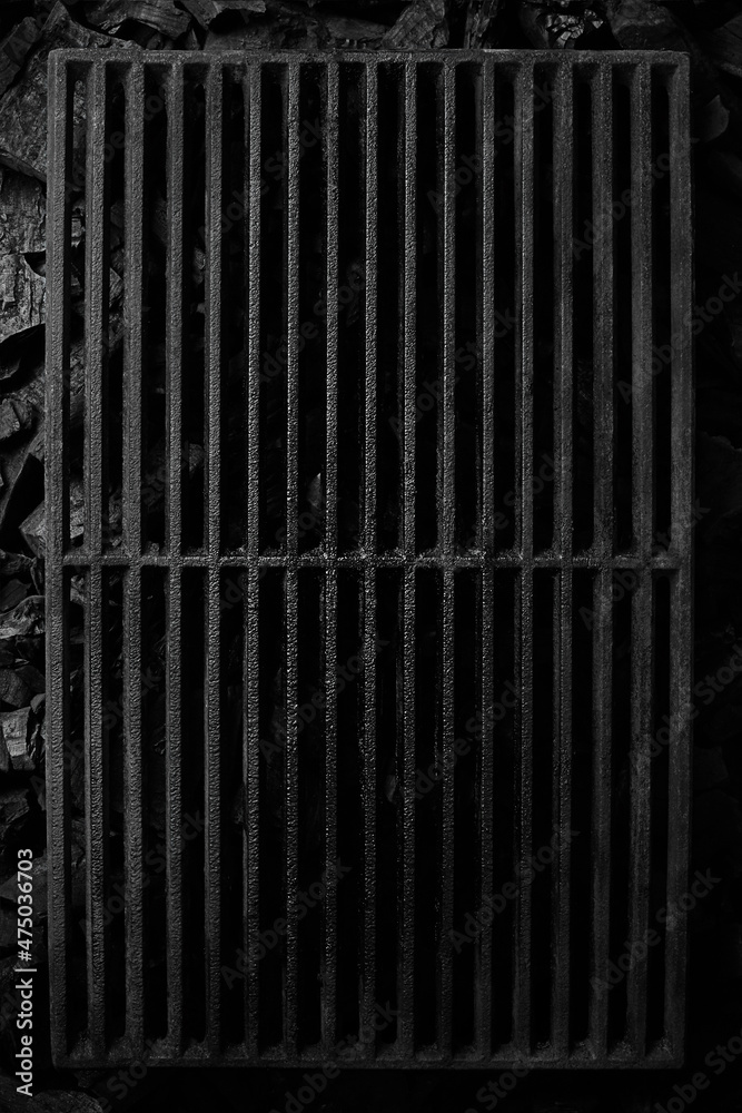 Top view of black cast iron grate over cold coals on grill