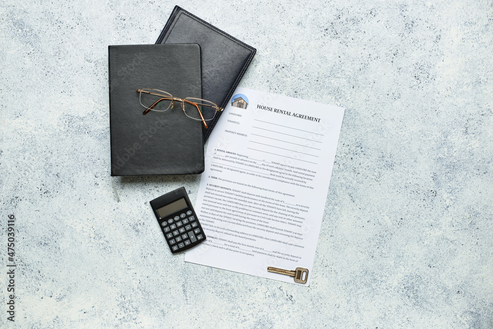 House rental agreement with calculator, notebooks, eyeglasses and key on grunge background
