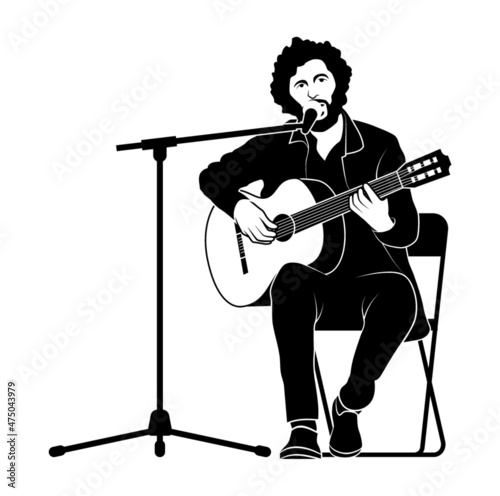Gitarrenspieler singt ins Mikrophon und sitzt auf einem Stuhl