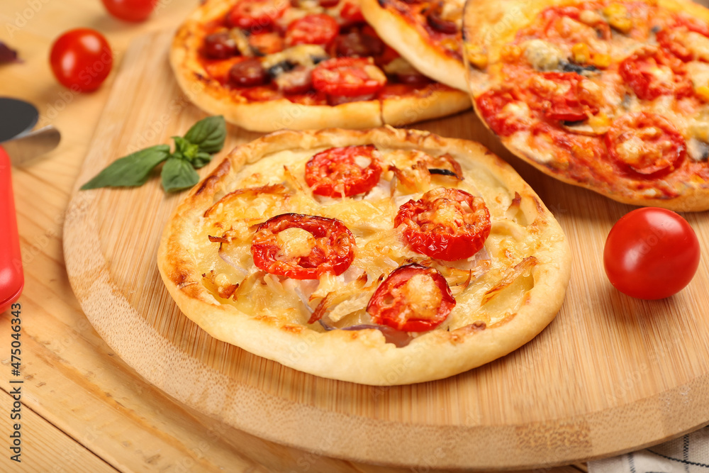 Board with delicious homemade mini pizzas on wooden background Board with delicious homemade mini pizzas on wooden background