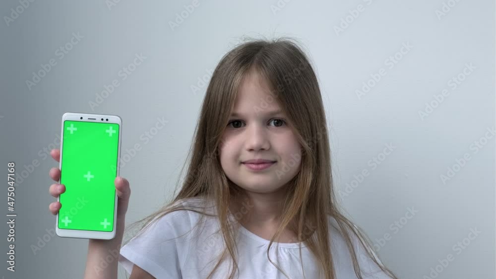 Cute child girl shows phone with green screen mock up cellphone, mobile, telephone. Chroma key green screen smartphone set up for advertising. Technology, gadget and kid. Children app presentation. Cute child girl shows phone with green screen mock up cellphone, mobile, telephone. Chroma key green screen smartphone set up for advertising. Technology, gadget and kid. Children app presentation.