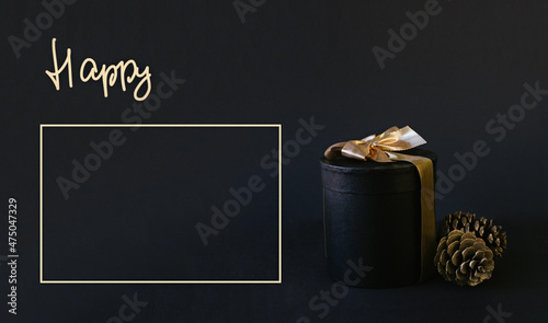 Black gift box with golden bow on black background for christmas and new year concept