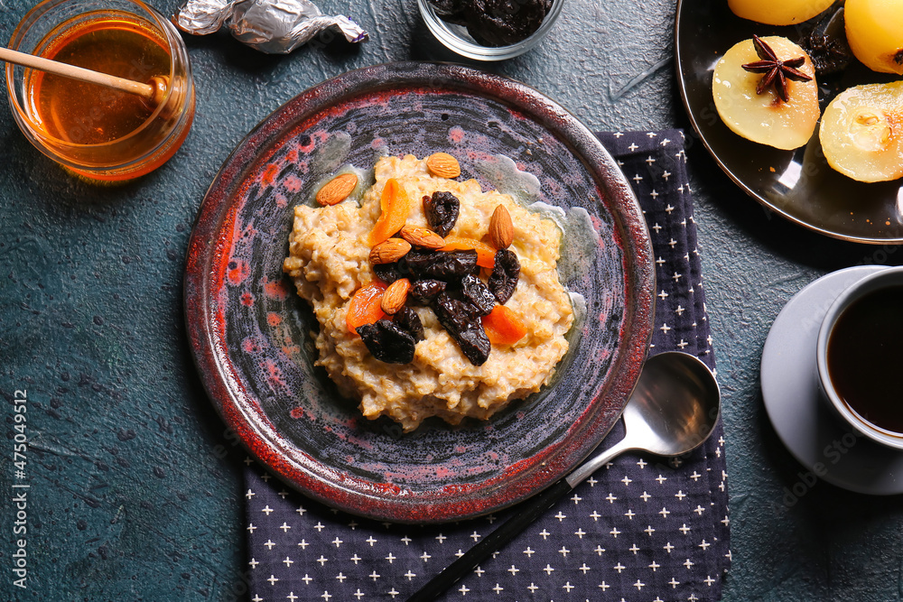 Plate with sweet oatmeal, prunes, dried apricots and almond nuts on dark table Plate with sweet oatmeal, prunes, dried apricots and almond nuts on dark table