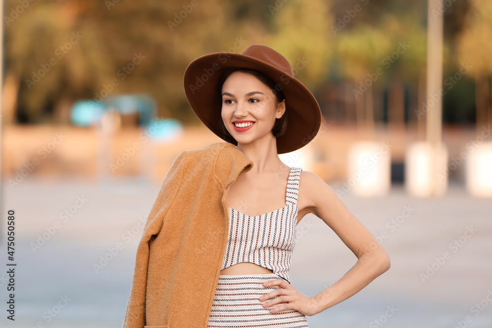 Young elegant woman with coat on her shoulder outdoors
