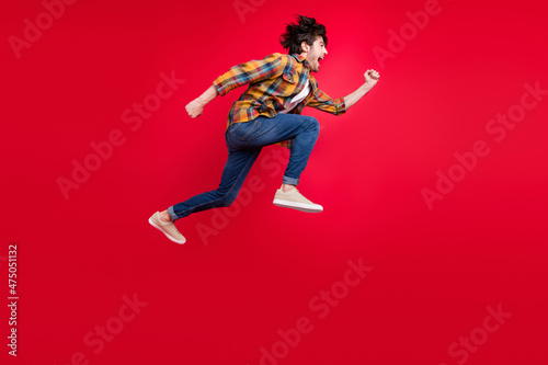 Photo of pretty charming young gentleman wear plaid outfit smiling jumping high running fast isolated red color background