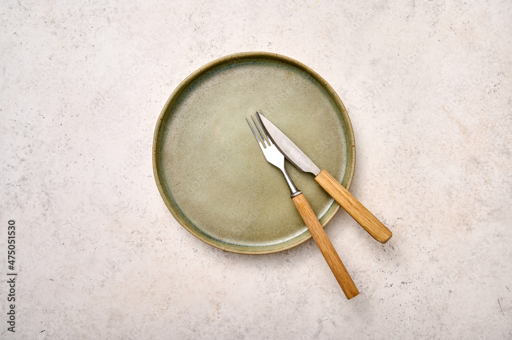 Flat lay empty green plate with fork and knife on white textured background. Design concept, copy space Flat lay empty green plate with fork and knife on white textured background. Design concept, copy space