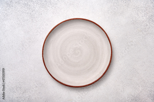 Fotografie, Obraz Empty white ceramic plate with brown rim on a light textured background, top vie