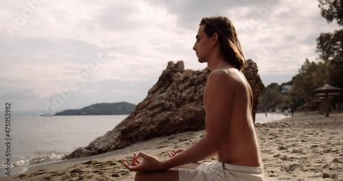 Caucasian male meditating on beach while on summer vacation