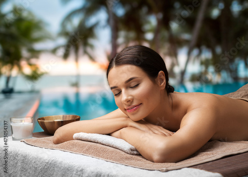 Photos wellness, beauty and relaxation concept - young woman lying at spa over tropical