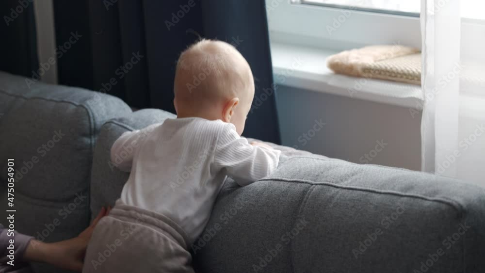 Cute baby boy standing by the window of apartment looking out the window at the street, child is waiting at home. High quality 4k footage Cute baby boy standing by the window of apartment looking out the window at the street, child is waiting at home. High quality 4k footage