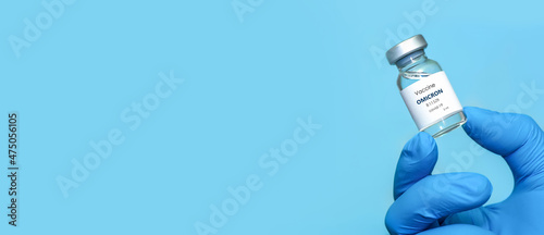 A doctor in medical gloves holds a bottle with coronavirus Covid19 Omicron variant strain vaccine.The concept of medicine, healthcare and science.Coronavirus vaccine.Banner. Copy space photo