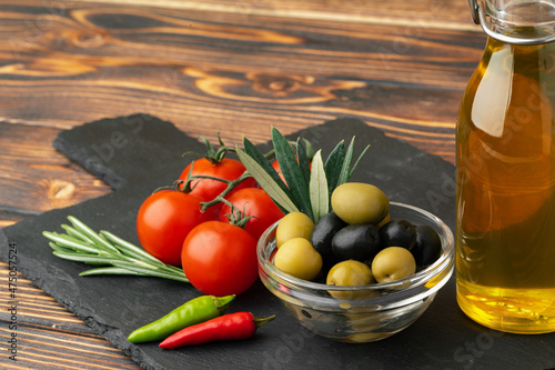 Olive oil, olives and tomatoes on wooden background