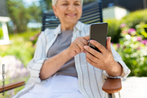 technology, old age and people concept - close up of happy smiling senior woman with smartphone resting at summer garden