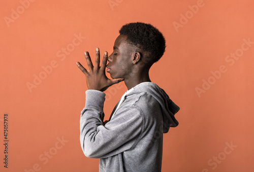 Fototapeta Naklejka Na Ścianę i Meble -  Calm young black guy with standing in orange studio win closed eyes