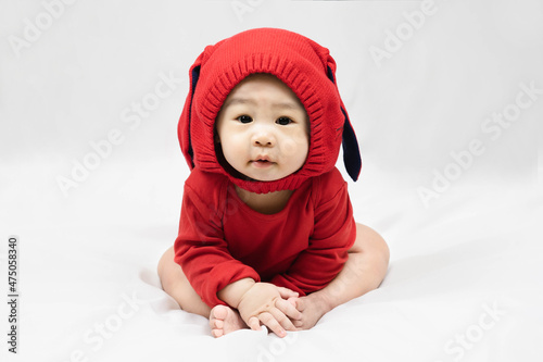 Happy infant baby boy toddler in red bodysuit and knitted hat with rabbit ears.Concept holiday Christmas, happy new year, infants, childhood.