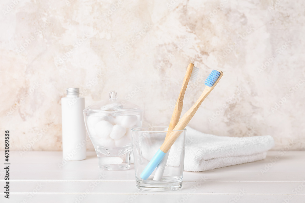 Glass with wooden toothbrushes on white wooden table
