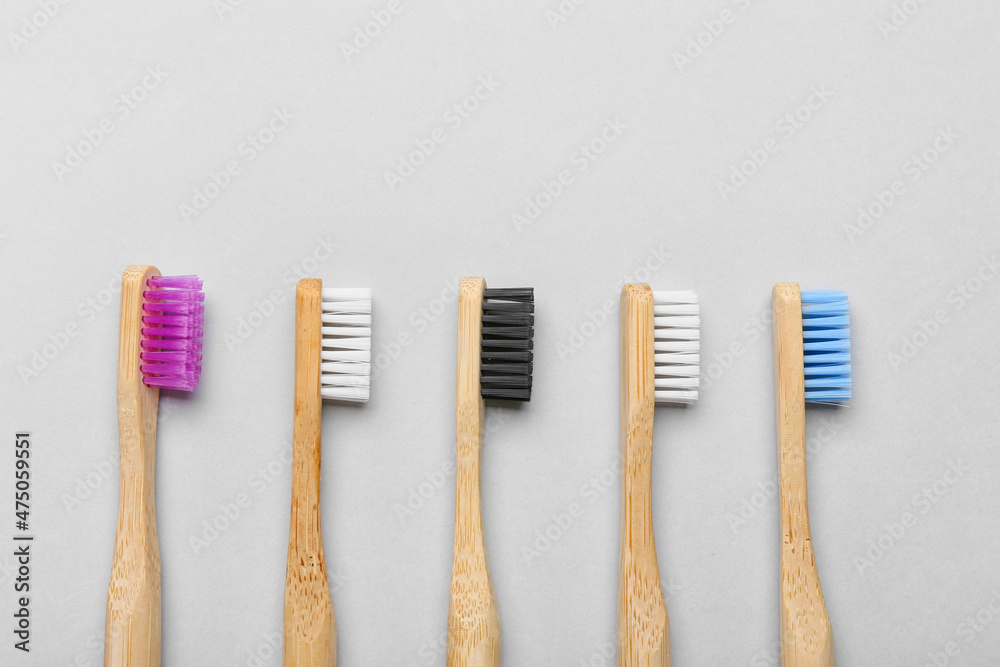 Different wooden toothbrushes on grey background, closeup